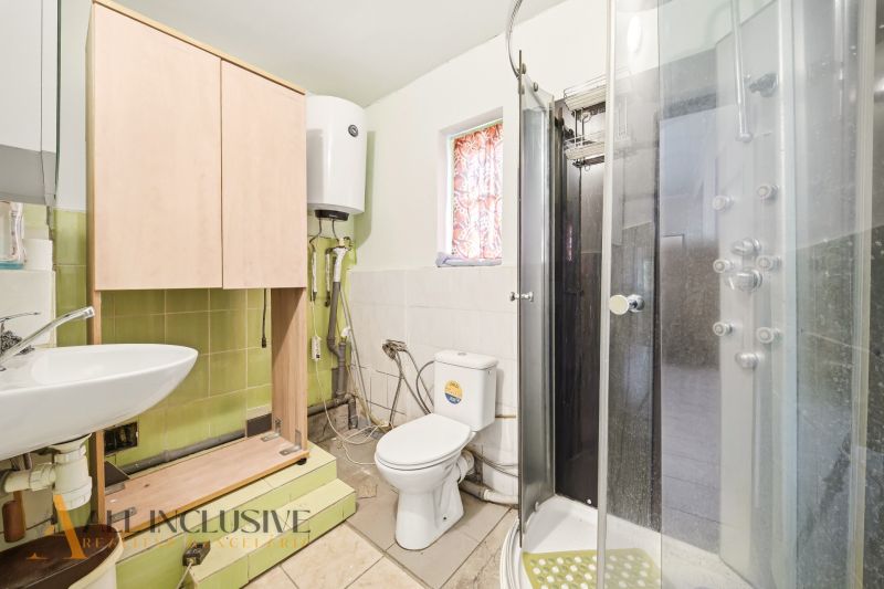 Bathroom with a sink, shower, cabinet, and toilet in a family house.