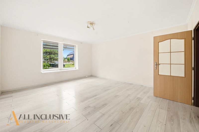 A bright room with a wooden decor floor and a large window in a family house.