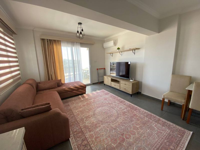 Living room of a three-room apartment with a sofa set and a television on a floor with a wooden decor.