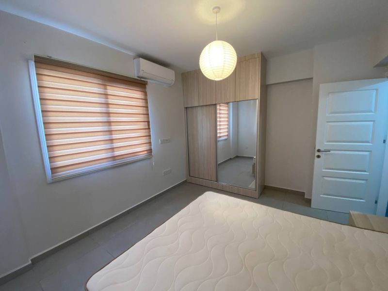 A bedroom in a 3-room apartment with a large mirrored wardrobe and curtains.