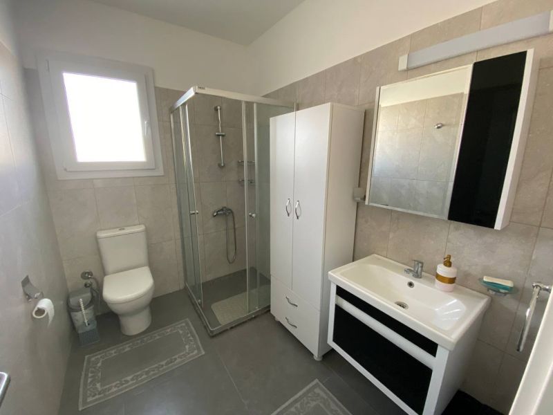 A bathroom in a 3-room apartment with a corner shower and simple furnishings.