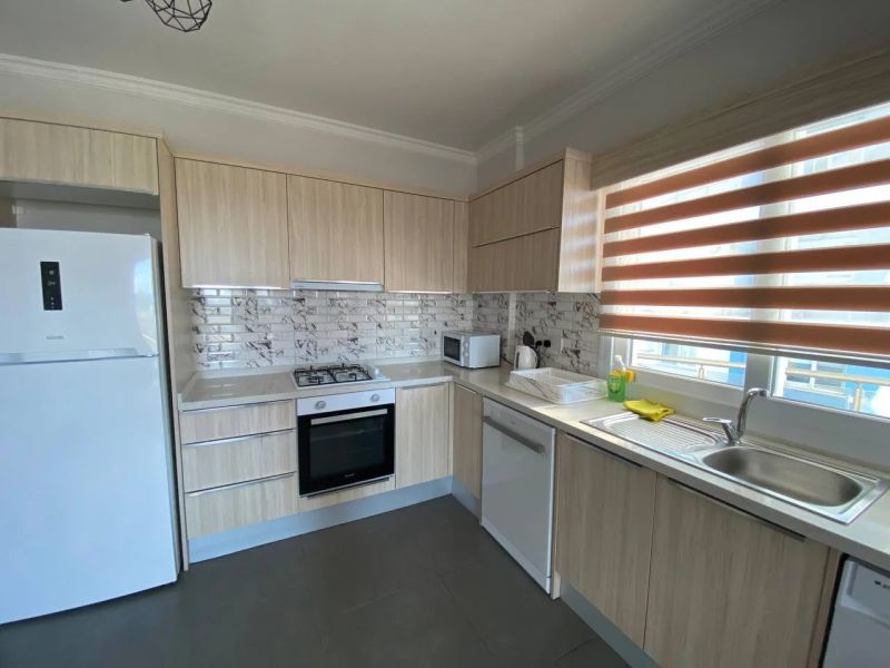 A kitchen in a 3-room apartment with white appliances and tiled backsplash.