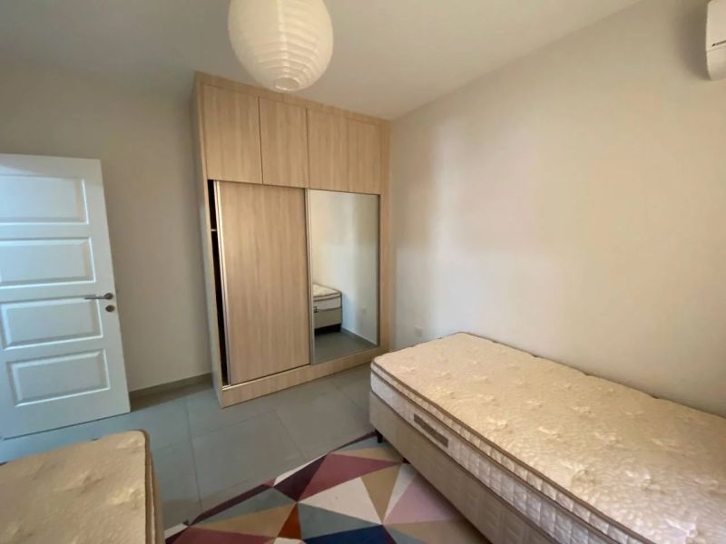 A bedroom in a three-room apartment with two beds, a wardrobe, and a colorful carpet.