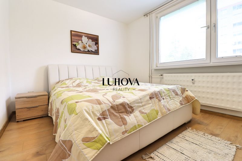 A bedroom in a 3-room apartment, wooden decor flooring, bed, nightstand.