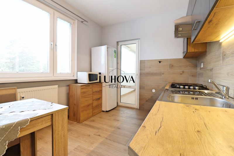 A kitchen in a 3-room apartment with a wooden floor decor and appliances.