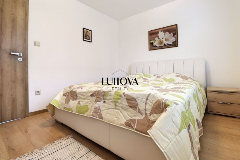 A bedroom in a 3-room apartment with a bed, blanket, and floor with a wooden decor.