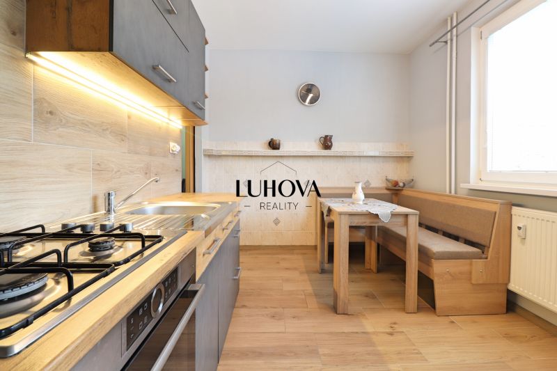 A kitchen in a 3-room apartment with a stove, a wooden table and a bench, a floor with a wooden decor.