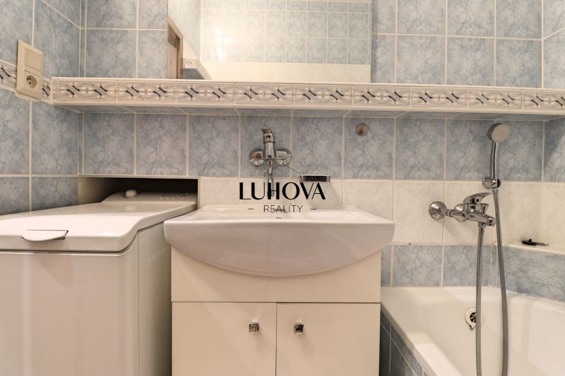 A bathroom with light blue tiles and a combination of a bathtub with a sink in a 3-room apartment.