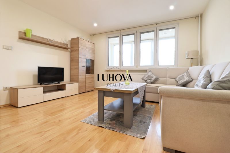 Living room in a 3-room apartment with a wooden decor floor, a sofa, and a TV stand.