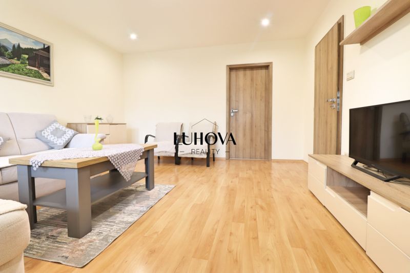 Living room of a three-room apartment with a wooden decor floor and light furniture.