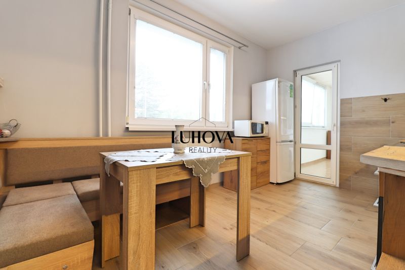 A kitchen in a 3-room apartment with a wooden decor floor and a dining table.
