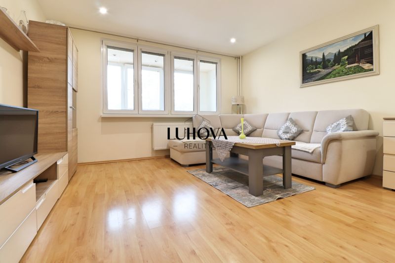 Living room in a 3-room apartment with a wooden decor floor, a light sofa, and a table.