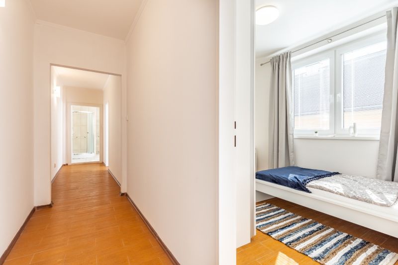 A hallway and a room with a light wooden-patterned floor in a 3-room apartment.