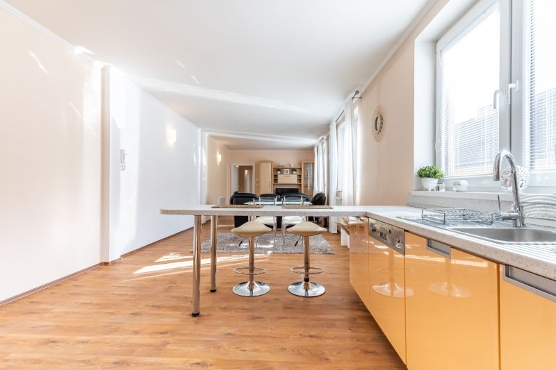 A kitchen in a 3-room apartment with an island and a floor with a wood decor.