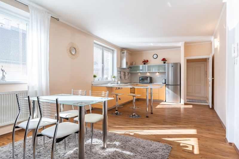 A kitchen in a 3-room apartment with a wooden decor floor and a dining table.