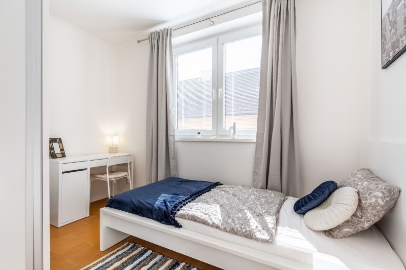 A bedroom with a single bed, a desk, and a wooden floor decor in a 3-room apartment.