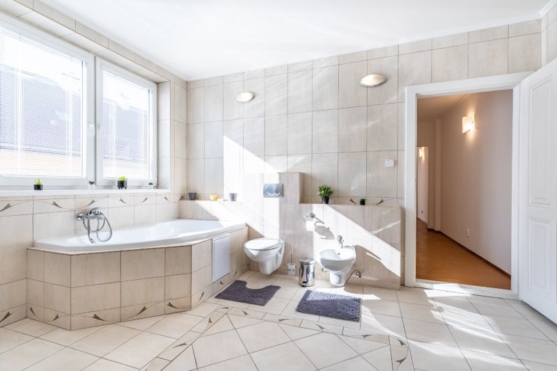 A bathroom in a 3-room apartment with a corner bathtub and light tiles.