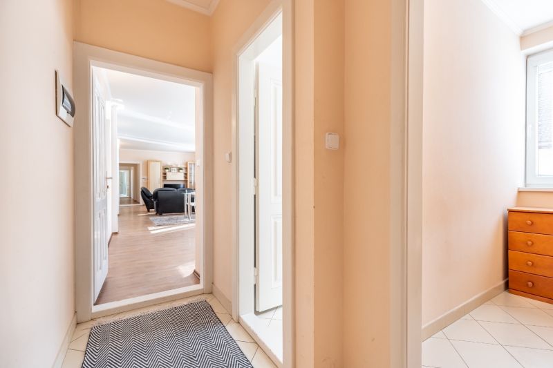 A hallway in a 3-room apartment with a wooden decor floor and furniture.