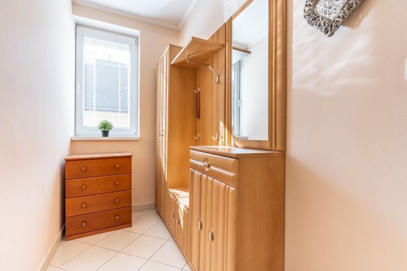 A narrow hallway with wooden furniture and tiles in a 3-room apartment.