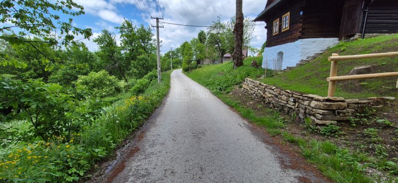 A narrow road path in Terchová surrounded by greenery, ideal for residential plots.