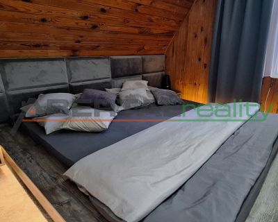 A bedroom in a cottage with a comfortable bed and wooden walls.