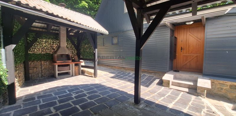 A cottage in Bukovec with a gazebo and an outdoor fireplace on a paved yard.