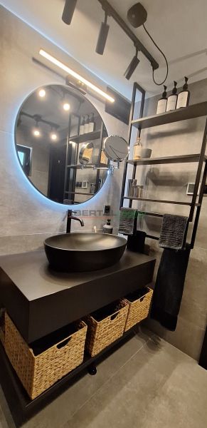 A bathroom in a cabin with a countertop sink, a round mirror, and storage baskets.