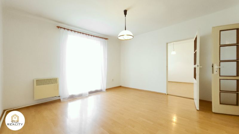 A bright room with a wood-decor floor in a 2-room apartment, curtain and light fixture.