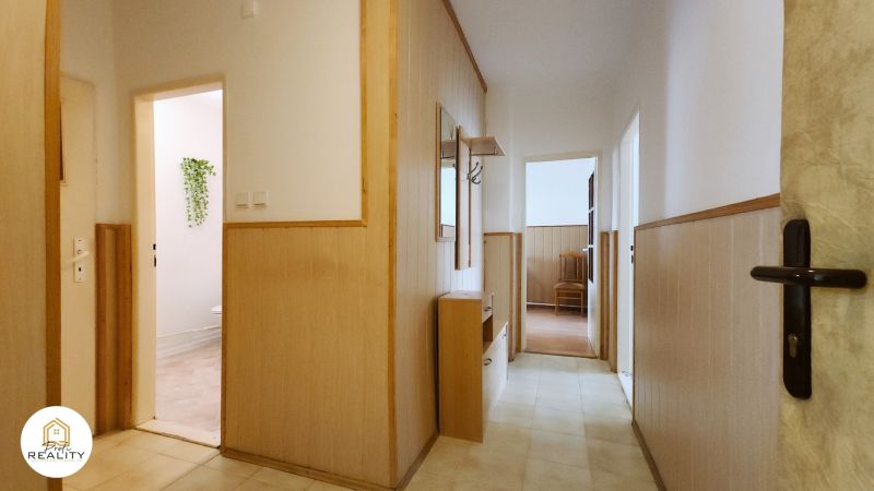 A hallway in a 2-room apartment with wooden paneling and floral decoration on the wall.