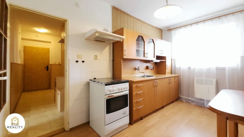The kitchen in a 2-room apartment with a wooden decor floor and a wooden kitchen unit.