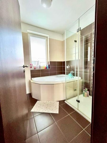A family house bathroom with a bathtub, shower, and brown-tinted tiles.
