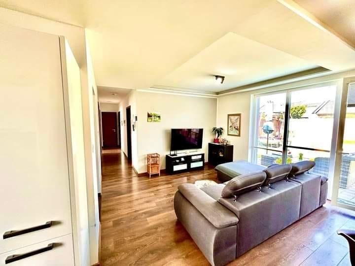 Living room in a family house with a wooden decor floor, a sofa, and a television.