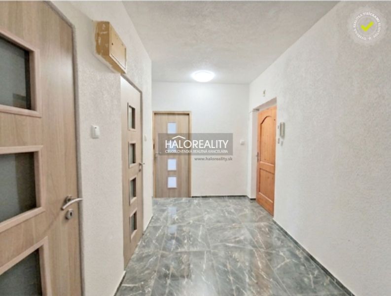 A hallway in a 2-room apartment with tiles and wooden doors.