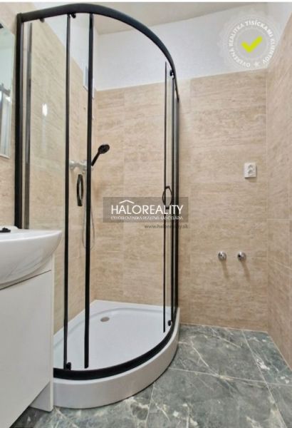 Shower corner in the bathroom of a 2-room apartment with tiles and a sink.