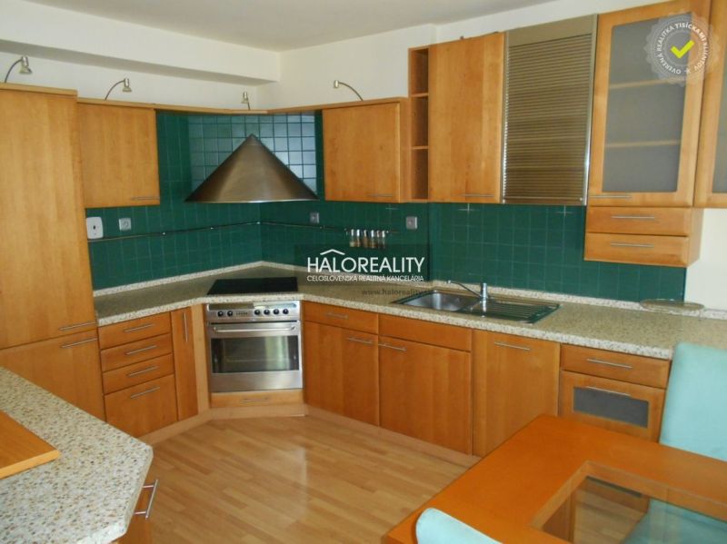 A kitchen in a 3-room apartment with a wooden decor floor and green tiles.