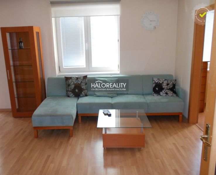 A living room with a blue sofa, a glass table, and a wooden decor floor in a three-room apartment.