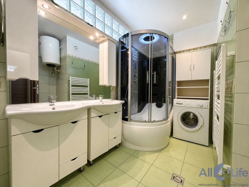 A bathroom in a 3-room apartment with two sinks and a shower.