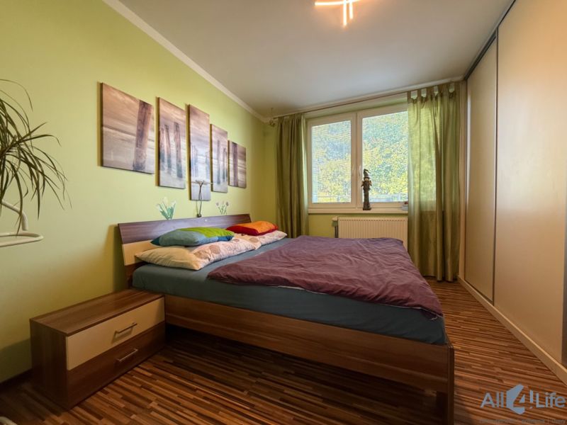 Bedroom in a 3-room apartment with a bed, nightstand, and floor with a wooden decor.