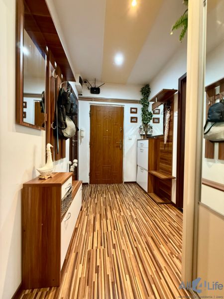 A hallway in a 3-room apartment with a wooden decor floor and wooden furniture.