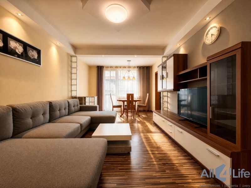 Living room in a three-room apartment with a sofa, TV wall, and wooden decor flooring.
