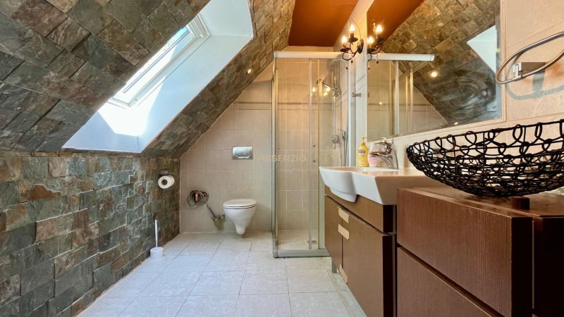 Attic bathroom with stone tiles and a shower in a family house.