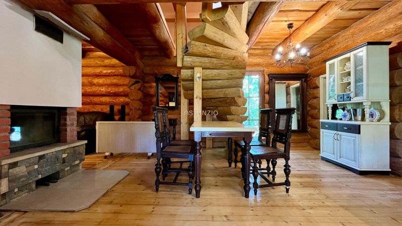 Interior of a family house with a wooden structure, fireplace, table, chairs, and a display cabinet.