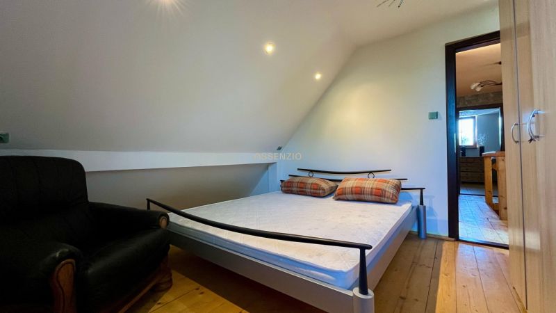 Bedroom with a bed and a chair in a family house, wooden floor, simple interior.