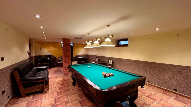 Interior of a family house with a billiard table, couch, and brick pillar.