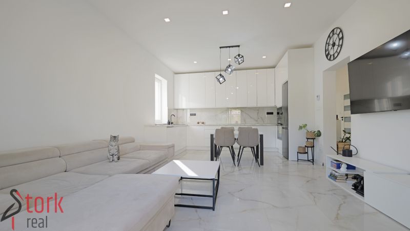 Interior of a family house with a white kitchen, sofa, and decorative elements on the walls.