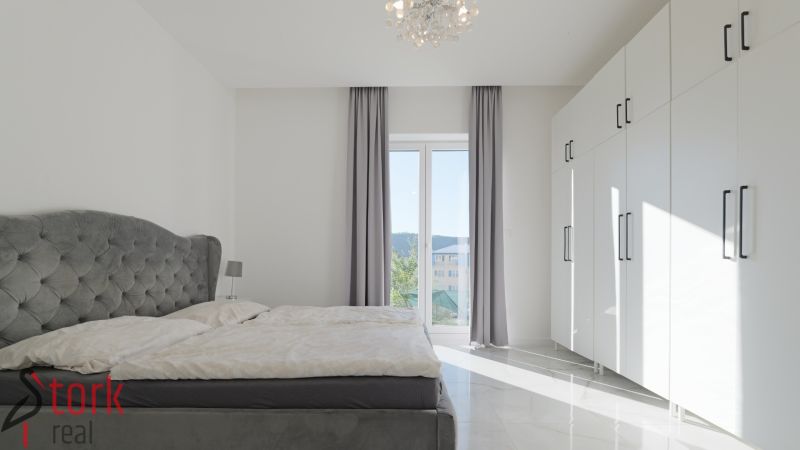 A bedroom with a large bed, white wardrobes, and curtains in a family house.