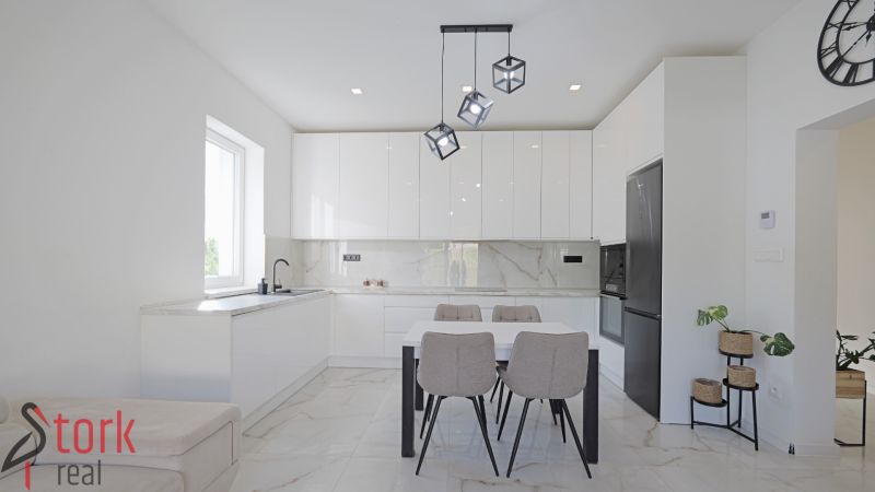 A kitchen in a family house with white cabinets, a dining table, and pendant lights.
