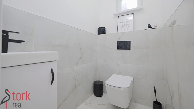 A bathroom in a family house with light tiles and black fixtures.