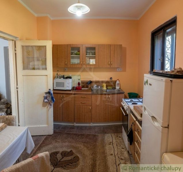 A kitchen in a family house with cabinets and appliances, a floor with a wooden decor.