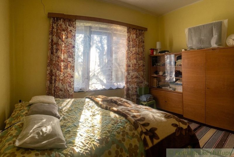 A room in a family house with a sunny window, a bed, and a wardrobe.